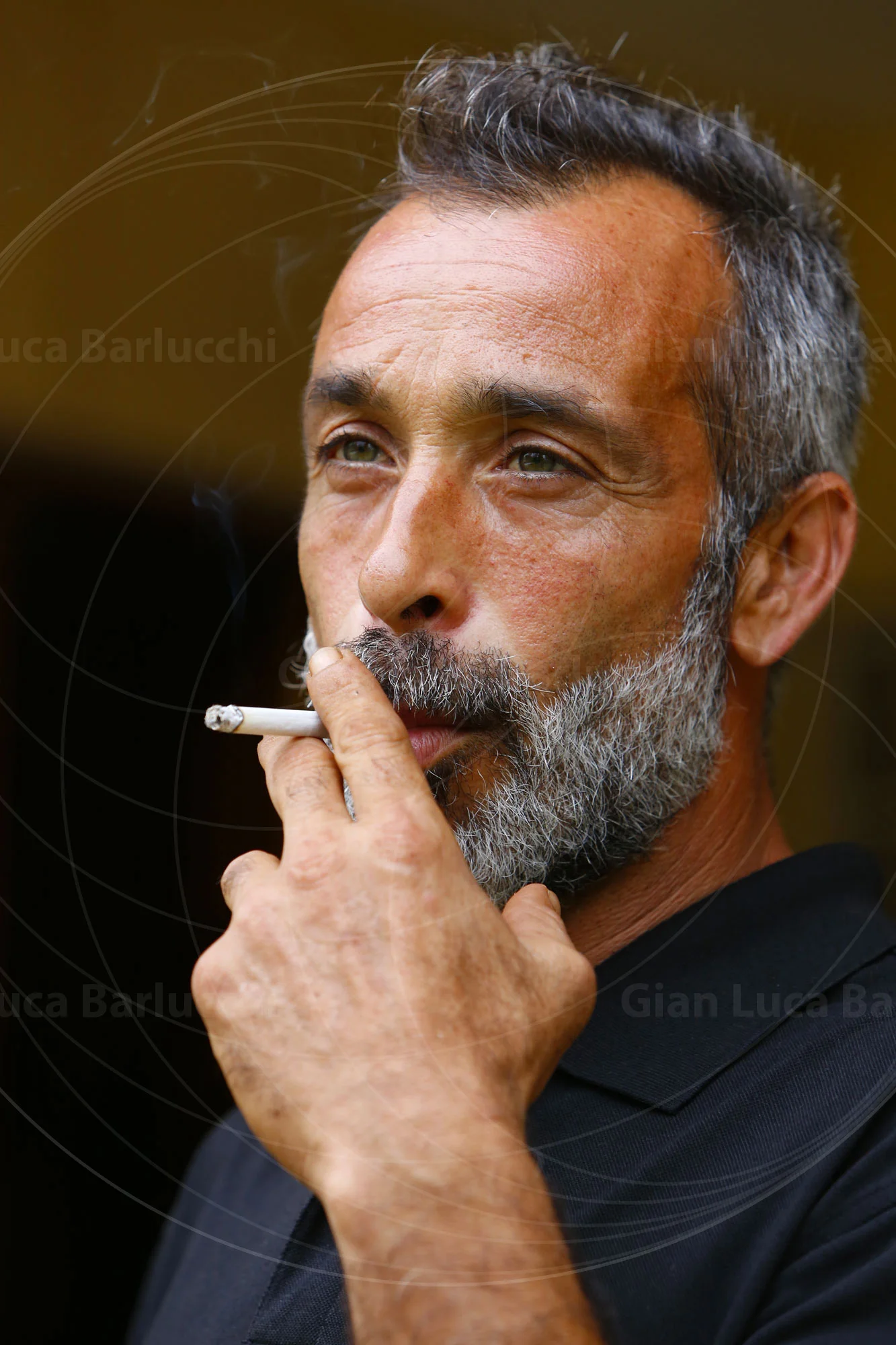 Portrait of a bearded man holding a cigarette near his face